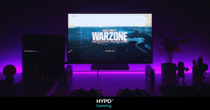 A sleek gaming desk illuminated by purple and blue LED lights with a monitor displaying Call of Duty.