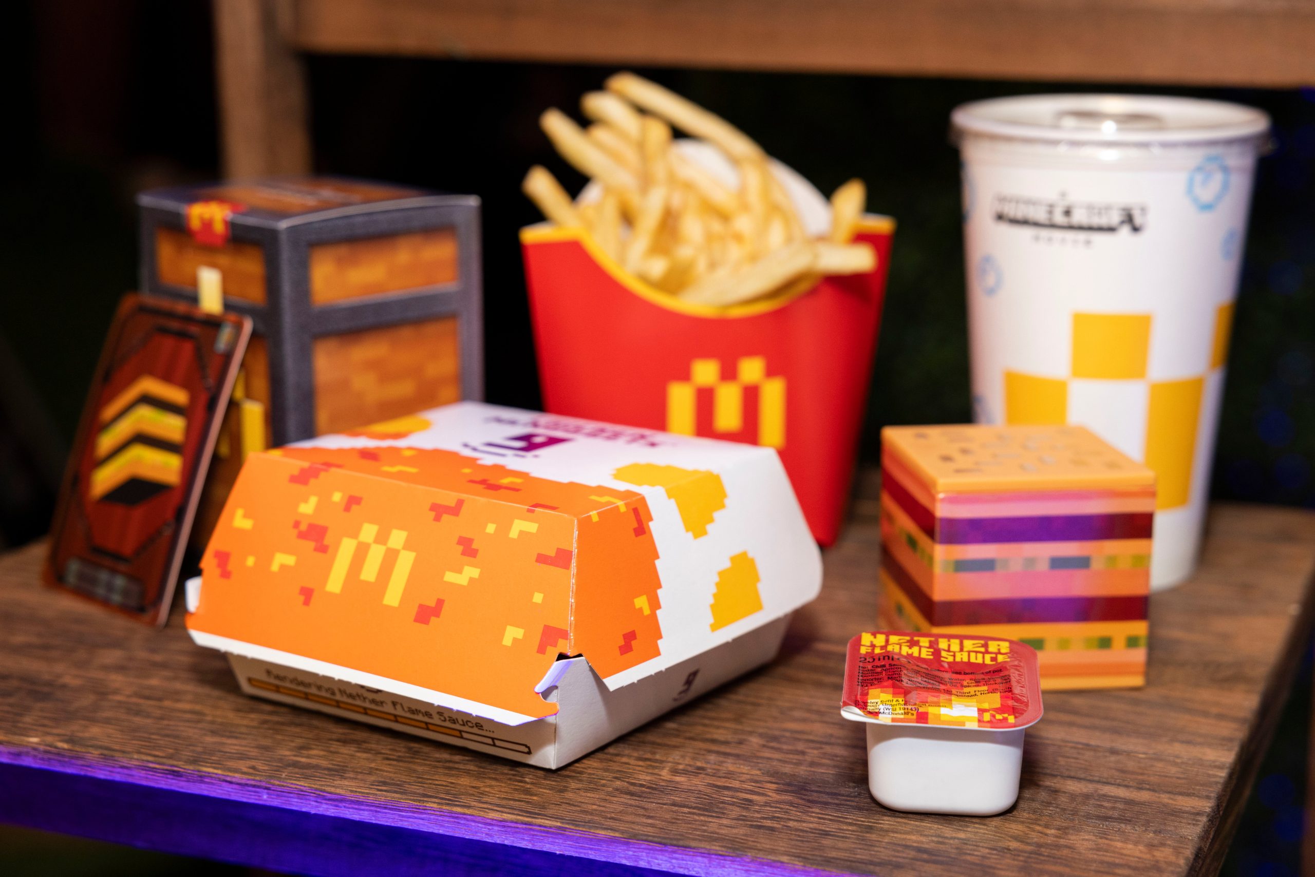 Gaming World News: A McDonald’s Minecraft-themed meal including fries, a drink, a burger box with pixelated design, Nether Flame Sauce, and collectible toys inspired by the game.