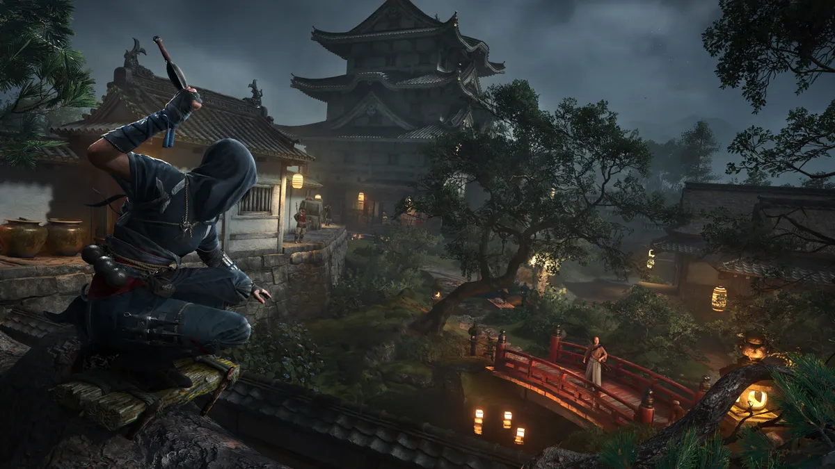 Assassin’s Creed Shadows screenshot of a shinobi poised to strike in a traditional Japanese village at night, with lanterns glowing and a fortress in the background.