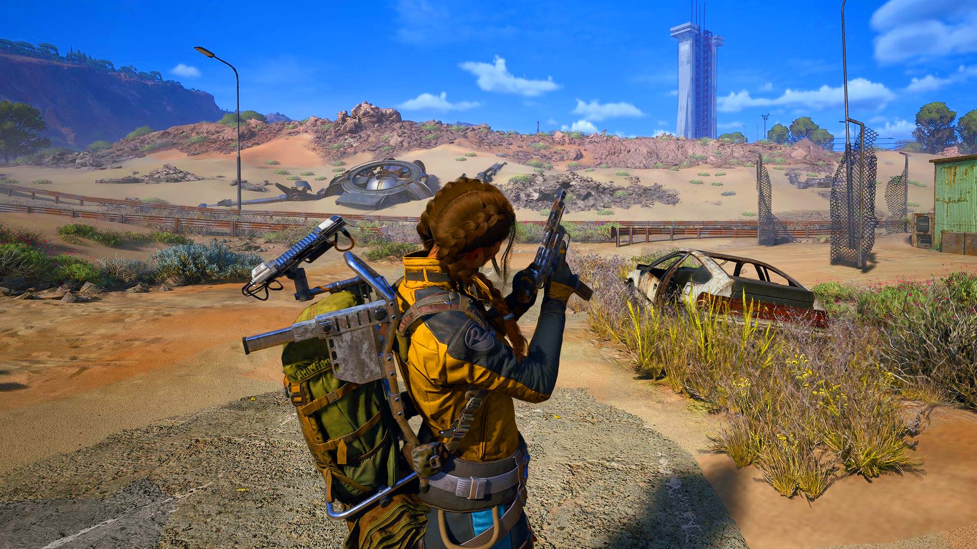 Player exploring a desert battlefield in ARC Raiders, aiming a weapon near wreckage with a crashed UFO and distant tower in view.