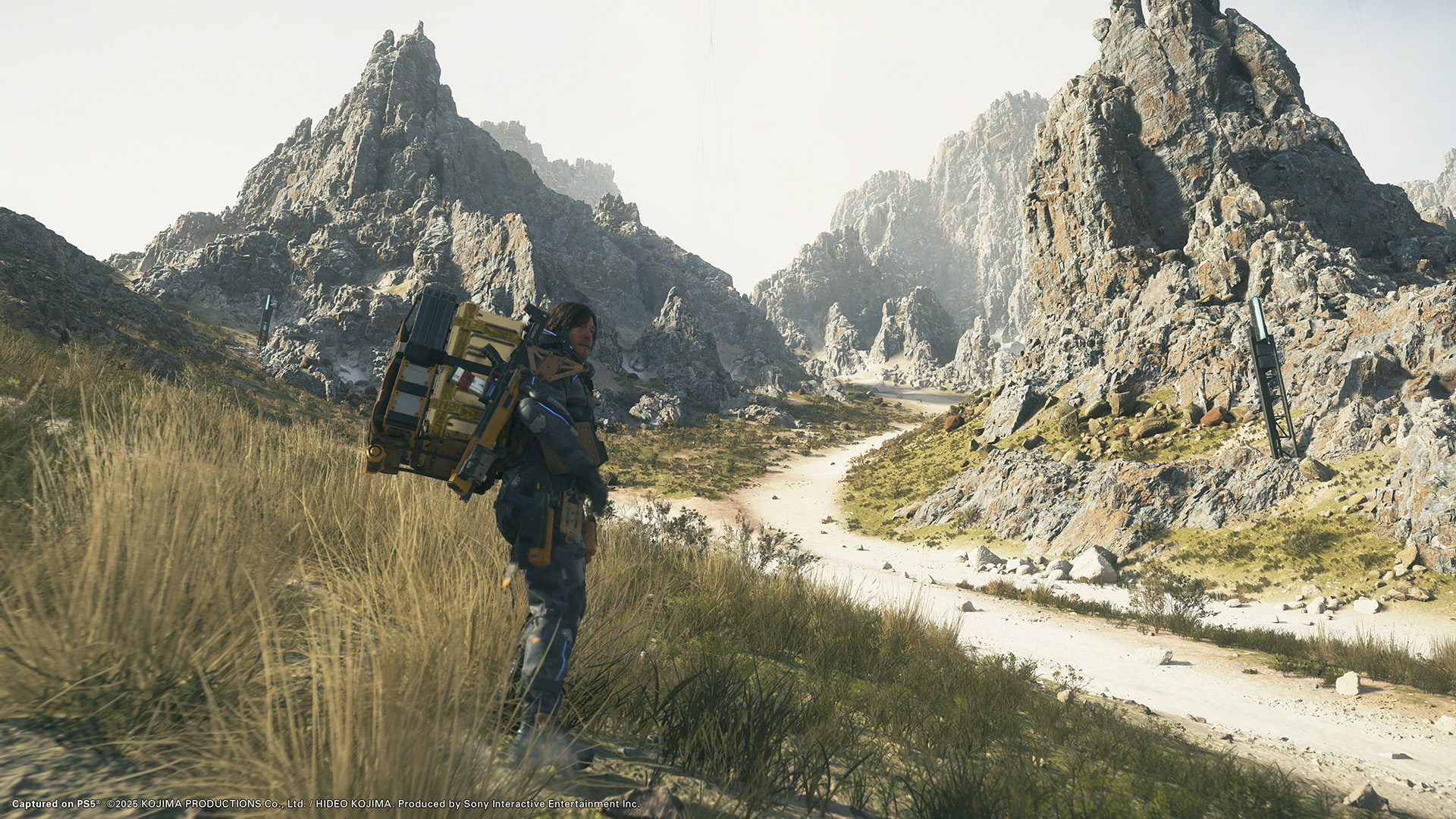 Character traversing a vast rocky landscape in Death Stranding 2: On the Beach, showcasing the game’s open-world terrain and cinematic design