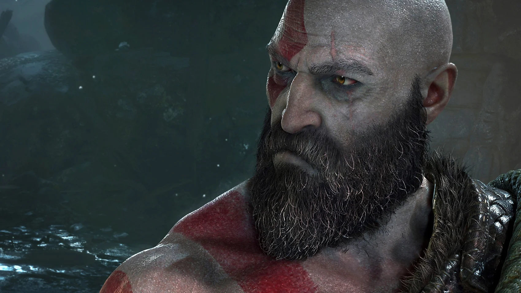 Close-up of Kratos in God of War, showing his red facial markings, thick beard, and intense expression against a dark forest backdrop.