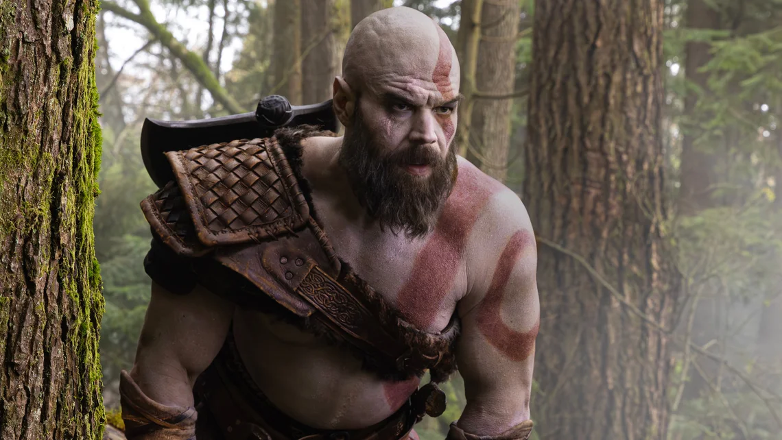 Ryan Hurst as Kratos in Amazon’s God of War TV series, standing in a forest wearing Norse armour with the iconic red war paint across his body.