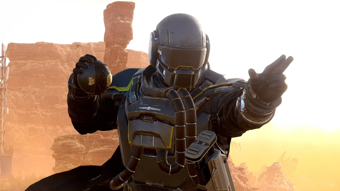 Helldivers 2 soldier in futuristic exosuit aiming weapons during intense desert battlefield combat