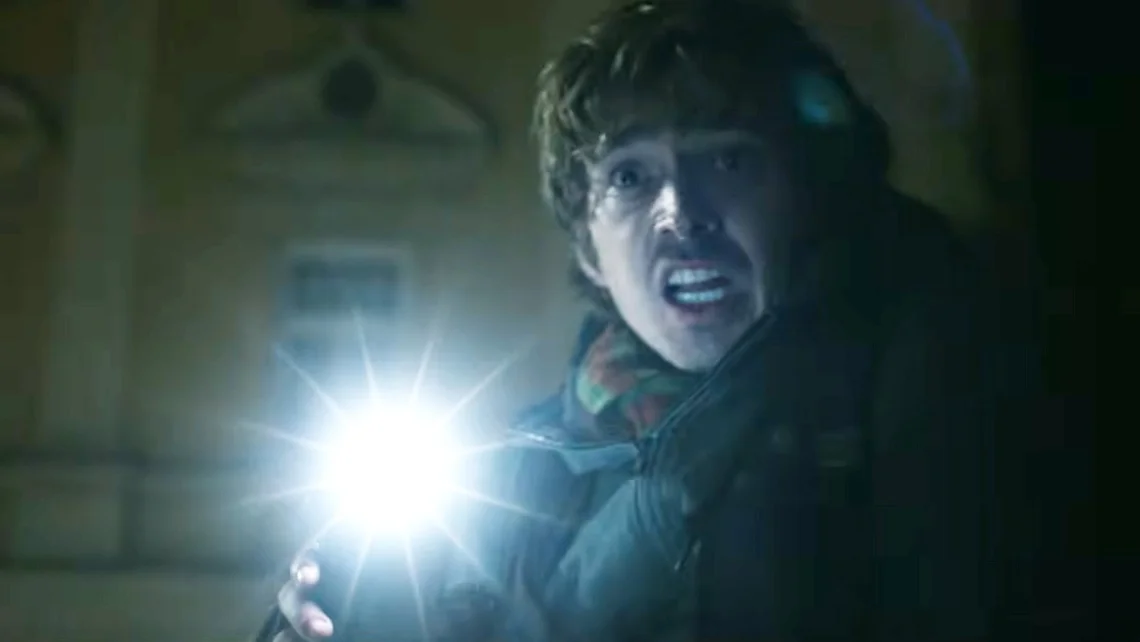 Character explores a dark hospital in the latest Resident Evil movie trailer, showcasing the film's eerie survival horror atmosphere.